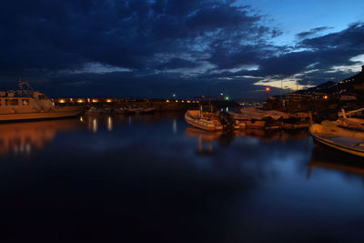 Boats moored in river against sky at dusk