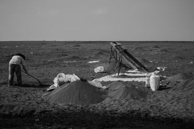 Man working on sea shore against sky