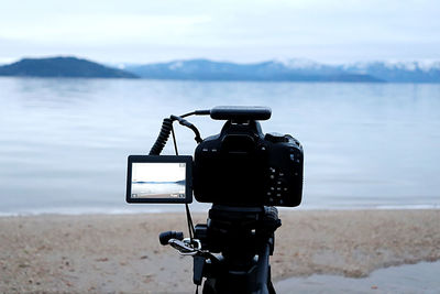 Camera photographing on beach against sky