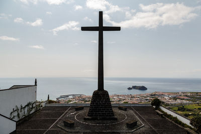 Cross by sea against sky