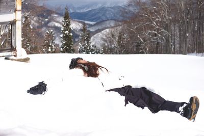 Woman lying on snow covered field