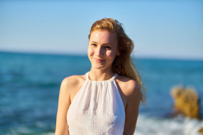 Portrait of smiling woman at beach against sky