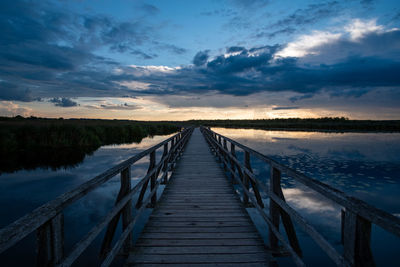 Wooden pier over lake against sky during sunset