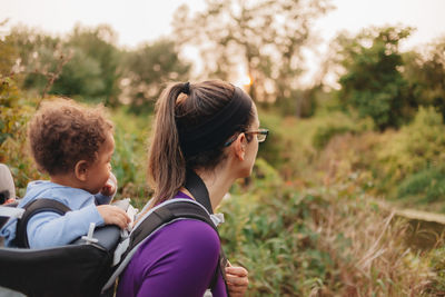 Mother carrying son while walking in forest