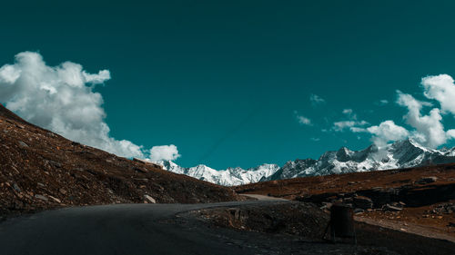 Scenic view of road by mountains against sky