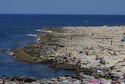 People standing on beach against clear sky