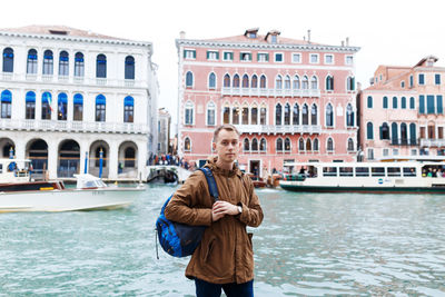 Young blond guy in a brown jacket in middle of streets of venice