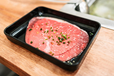 Premium rare slices of kagoshima wagyu a5 beef with marbled texture with chopped scallion and sesame