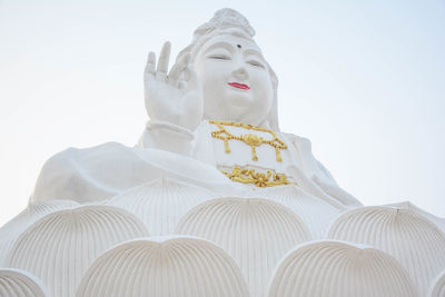 Low angle view of statue against temple against clear sky