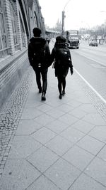 Rear view of people walking on street in city