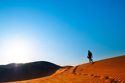 Man on desert against clear blue sky