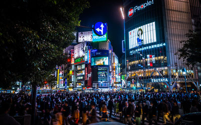 Crowd on illuminated street against sky at night