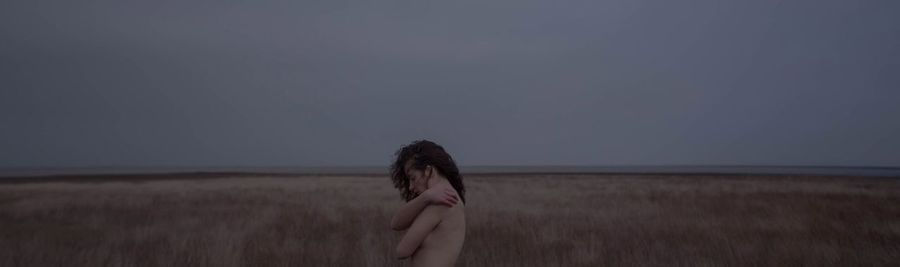 Rear view of woman standing on field against sky