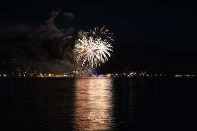 Golden fireworks glowing in the night sky and reflecting on water in tegernsee, bavaria, germany