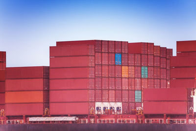 View of stacked container on ship against sky