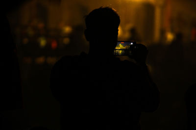 Rear view of silhouette man standing in city at night