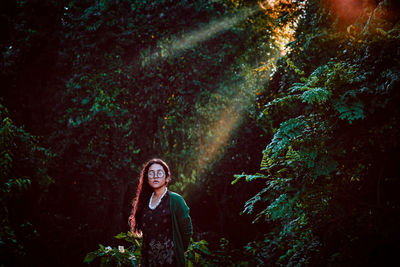 Portrait of smiling woman standing in forest