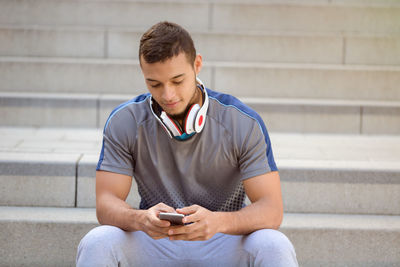 Mid adult man using mobile phone while sitting on staircase