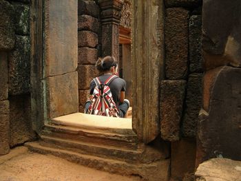 Rear view of tired woman sitting at temple old ruins