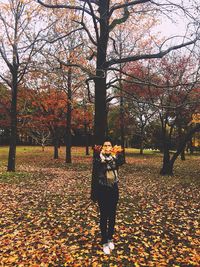 Woman standing by tree in park during autumn