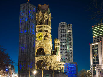 Low angle view of illuminated buildings against blue sky
