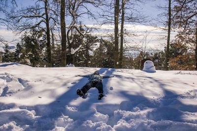 Boy on snowy field against sky during winter