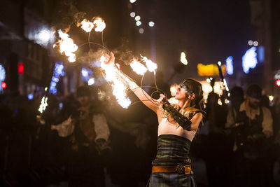 Woman standing by illuminated lighting equipment at night