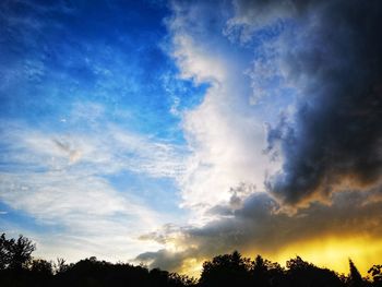 Low angle view of silhouette trees against dramatic sky