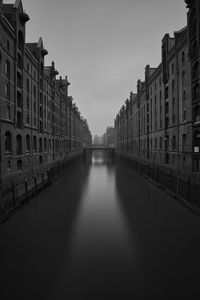 Canal amidst buildings against sky in city