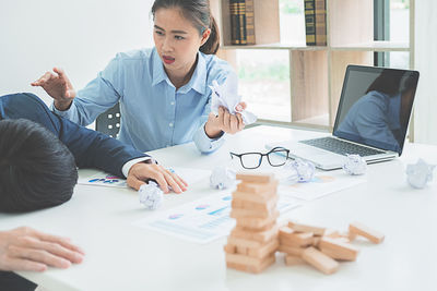 Tensed business colleagues with crumpled paper at desk in office