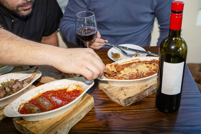 Close-up view of two men sharing a meal together with a bottle of wine