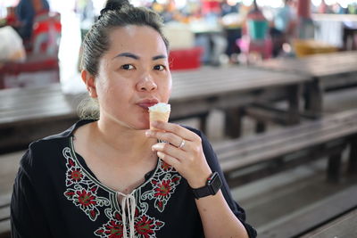 Portrait of mid adult woman eating ice cream at restaurant