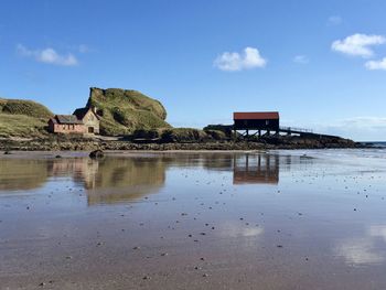 Boat house on beach against sky