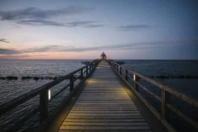 Pier over sea against sky during sunset