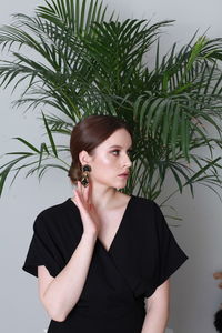 Portrait of young woman standing against plants