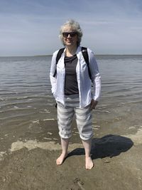 Full length of woman standing at beach against sky