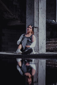 Portrait of smiling young woman standing against brick wall