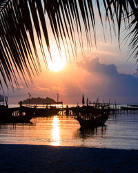 Silhouette boats in sea against sky during sunset