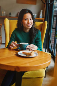 Portrait of young woman sitting on table