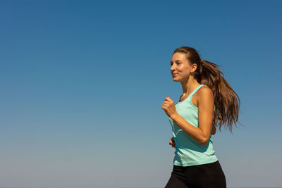 Low angle view of woman running against sky