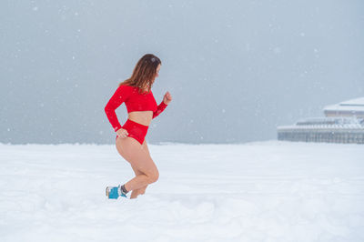 Woman jogging on snow covered land during winter