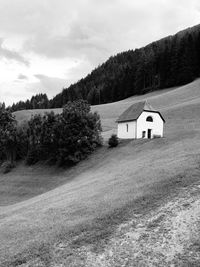 House on field by mountain against sky
