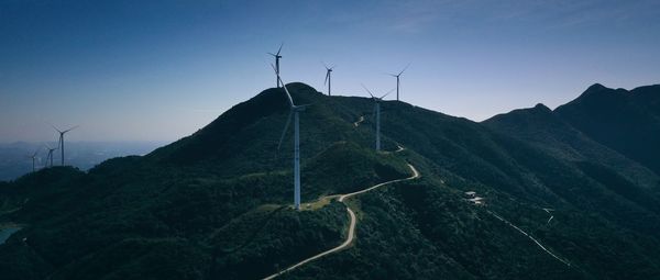 Wind turbines on landscape against sky