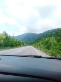 Road seen through car windshield against sky