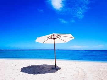 Lifeguard hut on beach against blue sky