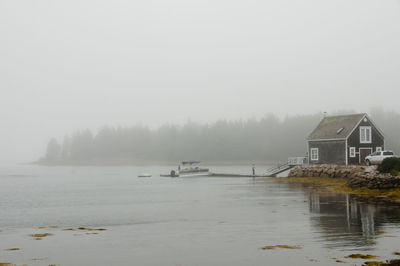 Scenic view of lake and buildings against sky during winter