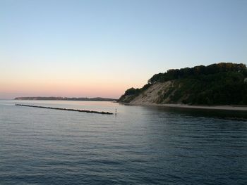 Scenic view of calm sea against clear sky at sunset