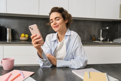 Portrait of young woman using mobile phone in office