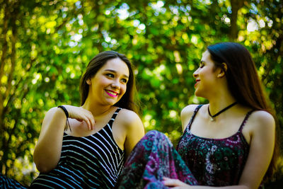 Smiling friends talking while sitting at park