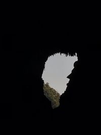 Low angle view of silhouette rock formation against clear sky